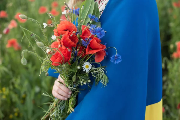 带着花束的女孩肩上扛着飘扬的蓝色和黄色国旗 走在罂粟地里 乌克兰独立日和国旗日概念 — 图库照片