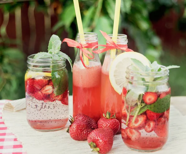 Fresa y menta infundido agua de desintoxicación. Limonada de fresa con hielo y menta como bebida refrescante de verano en frascos. Refrescos fríos con fruta . — Foto de Stock