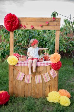 Limonata standında oturan çilek serinletici içecekler ile sevimli küçük kız 