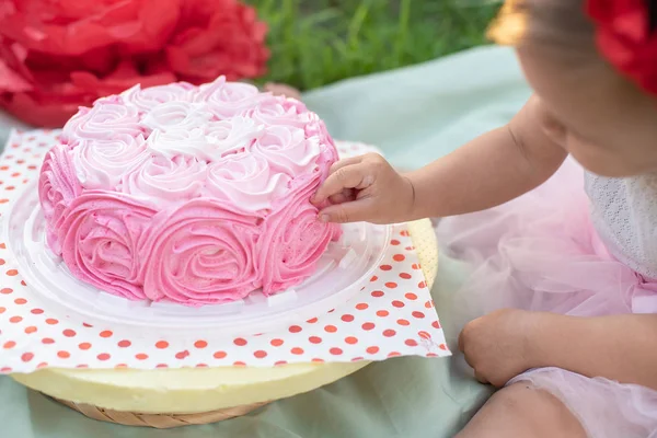 緑の草の中でお祝いの飾りとバースデーケーキの近くに座っている2歳の女の子 — ストック写真