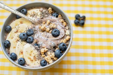Sağlıklı kahvaltı Berry Smoothie kase yaban mersini ve Chia tohumları ile muz ve granola ile tepesinde. Vegan ham gıda kavramı 