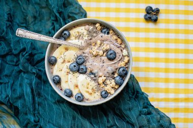 Sağlıklı kahvaltı Berry Smoothie kase yaban mersini ve Chia tohumları ile muz ve granola ile tepesinde. Vegan ham gıda kavramı 