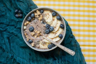 Sağlıklı kahvaltı Berry Smoothie kase yaban mersini ve Chia tohumları ile muz ve granola ile tepesinde. Vegan ham gıda kavramı 