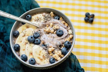 Sağlıklı kahvaltı Berry Smoothie kase yaban mersini ve Chia tohumları ile muz ve granola ile tepesinde. Vegan ham gıda kavramı 