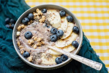 Sağlıklı kahvaltı Berry Smoothie kase yaban mersini ve Chia tohumları ile muz ve granola ile tepesinde. Vegan ham gıda kavramı 