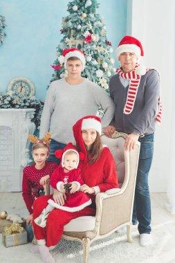 Neşe ve mutluluk kavramı. Büyük aile toplantısının portresi. Yerde oturuyor, hediyeler alıyor, büyük aile fotoğrafı çekiyor anne, baba, iki oğlan ve küçük kız. Çocuklar Noel hediyelerini açıyor..