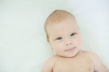 Mavi gözlü küçük sevimli üç aylık kız bebek kamera bakarak ve beyaz battaniye üzerinde yalan yakın çekim. Bebek bakım konsepti