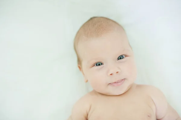 小可爱的三个月大的女婴的特写镜头 蓝眼睛看着相机 躺在白色的毯子上 婴儿护理概念 — 图库照片