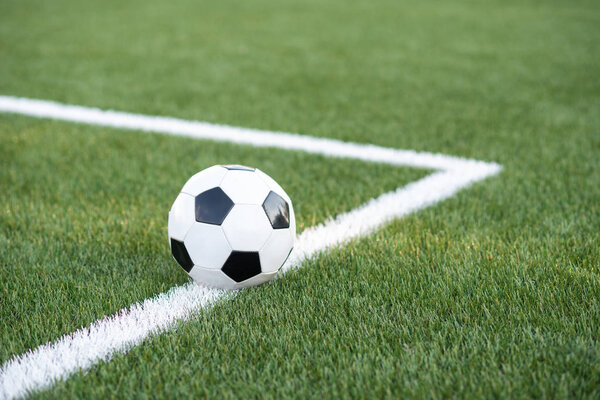 Традиционный черно-белый мяч на зеленой траве футбольного стадиона
