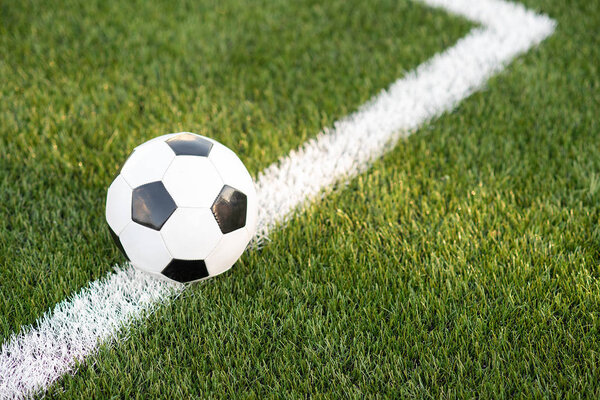 Традиционный черно-белый мяч на зеленой траве футбольного стадиона
