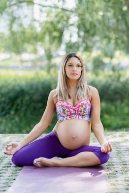 Hamile, dışarıda yoga yapıyor. Doğum öncesi yoga ve gelecekteki anne esneme egzersizleri yapıyor..