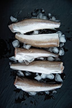 Koyu arka plan üzerinde buz ile çiğ balık hake fileto, üst görünümü