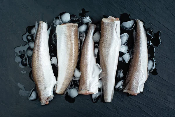 Koyu arka plan üzerinde buz ile çiğ balık hake fileto, üst görünümü 