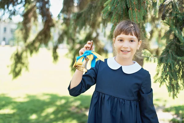 Portrait of beautiful young Schoolgirl on background school. Farewell Bell. day of knowledge. beginning of school year. Child with bell
