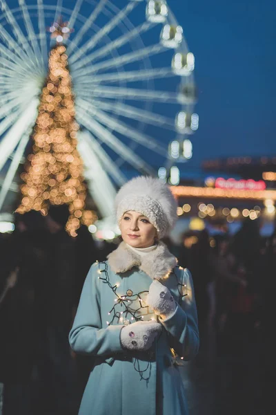 冬の雪の日に屋外のクリスマスマーケットで暖かい服のかわいい女の子 クリスマスビッグフェリスホイールライト 休暇や冬や人々の概念は — ストック写真