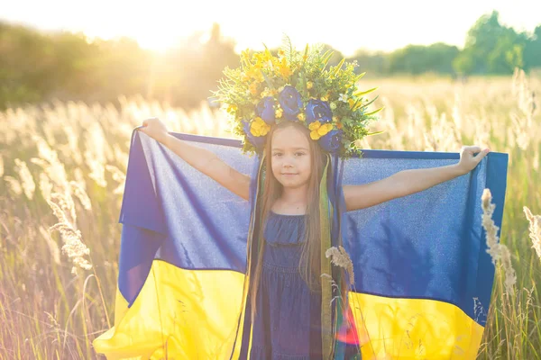 Meisje draagt fladderende blauwe en gele vlag van Oekraïne in het veld. — Stockfoto