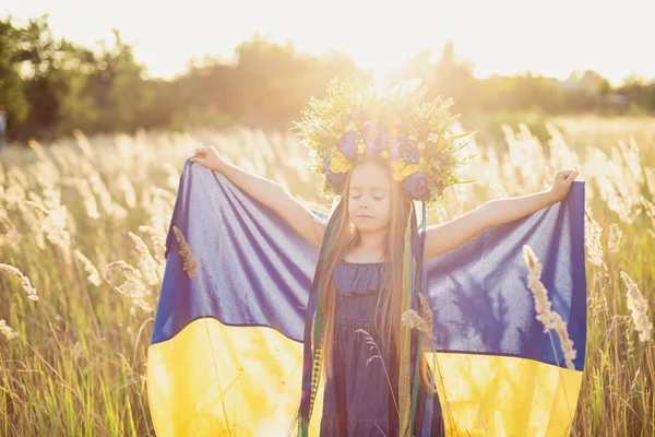 Meisje draagt fladderende blauwe en gele vlag van Oekraïne in het veld. — Stockfoto