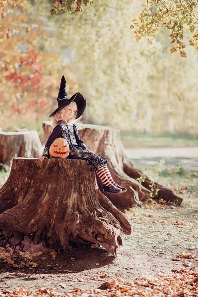 Klein meisje in heks kostuum vieren Halloween buiten en veel plezier. — Stockfoto