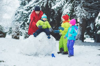 Anne ve üç çocuk karlı kış ormanlarında oynuyorlar, Noel tatili konsepti 