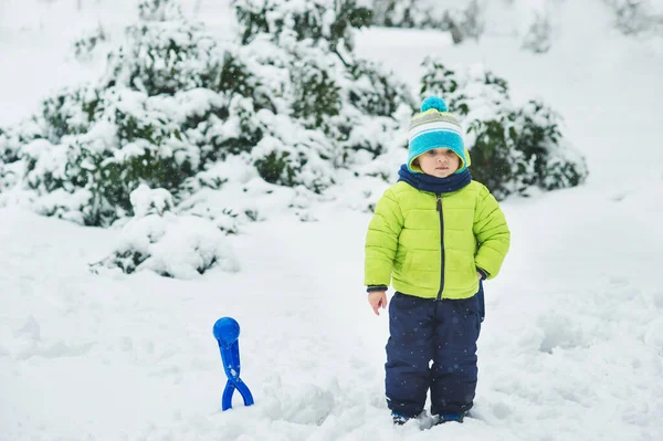 Liten Pojke Bär Varma Kläder Med Snöbollstillverkare Stående Snöig Vinterskog — Stockfoto