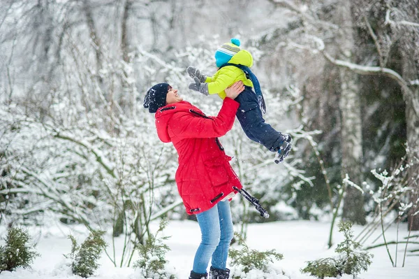 快乐的母亲牵着儿子在雪地的冬季森林里玩耍 — 图库照片