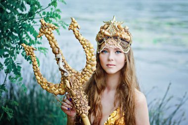 Fantezi kadın gerçek deniz kızı deniz tanrıçası altın kuyruklu deniz tanrıçası gün batımında kayalarda oturuyor altın saçlı taç inci kabuk takıyor. Deniz kızı kıyıda oturuyor. fantezi kavramı.