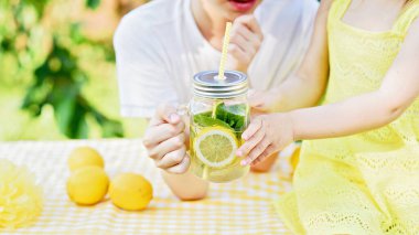 Çocuklar parkta doğal limonata içerler. Yaz ferahlatıcı doğal limonata. Detoks meyvesi aromalı su, içecek kutusunda taze meyveli kokteyl.