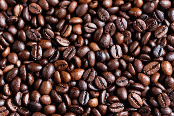closeup of perfect Roasted coffee beans background. Food ingredients, top view, space for text. Soft selective focus. Cappuccino, aroma black caffeine drink ingredient for coffee beverage. Coffee Shop
