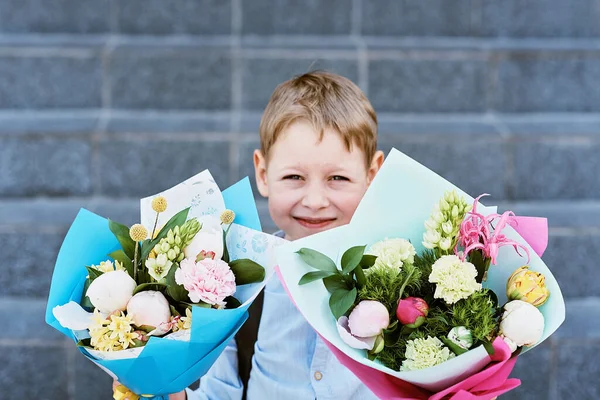 bouquet for first beloved teacher on first September. Flowers for last bell. day of knowledge. beginning of school year. first-grader with bouquet in school uniform on background of school