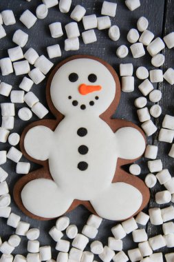 Gri ahşap arka planda şekerli zencefilli kardan adam. Noel veya Yeni Yıl kompozisyonu. Noel kartı. Üst Manzara. Düz yatıyordu. Noel konsepti. Tatil geçmişi. Boşluğu kopyala.