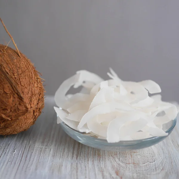 Hindistan cevizi ve küçük cam kase hindistan cevizi cipsi.