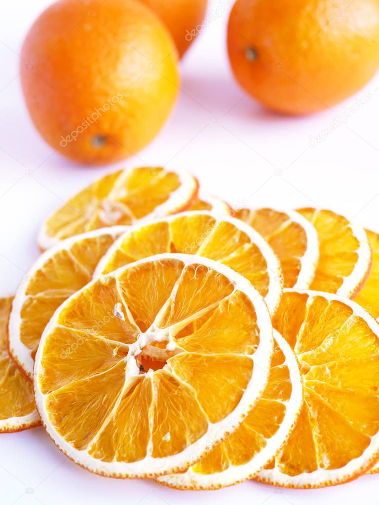 fresh whole oranges and dried orange slices on white surface
