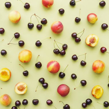 Yeşil arka plan düz bir üst manzarada kiraz ve şeftali. Meyve deseni.