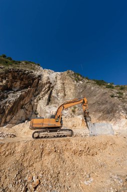 Turuncu izci Ekskavatör Apuan Alps (Alpi Apuane) mermer ocağı (Carrara beyaz mermer) matkap ile. Toskana, (Toscana), İtalya, Europe