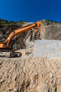 Turuncu izci Ekskavatör Apuan Alps (Alpi Apuane) mermer ocağı (Carrara beyaz mermer) matkap ile. Toskana, (Toscana), İtalya, Europe