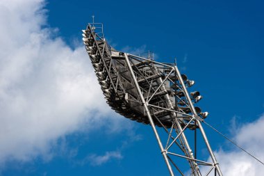 Aydınlatma donanımları ile modern bir stadyum üzerinde mavi bir gökyüzü bulutlu metal bir yapıda asılı birçok elektrik spot