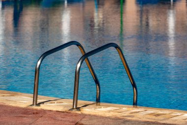 Bir yüzme havuzu ile paslanmaz çelik ve masmavi bir deniz bir merdiveni Close-up