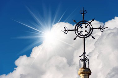 Dövme demir haç üzerinde mavi bir gökyüzü bulutlar ve güneş ışınları, Hıristiyan dini sembol ile. Kilise Kutsal Yürek La Spezia, Liguria, İtalya