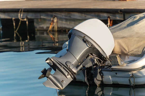 Detail of one outboard motor (engine and propeller), on a boat moored in the port with reflections