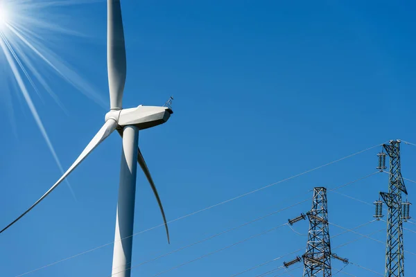 風力タービンと澄んだ青空と太陽光線 再生可能エネルギーの概念の高電圧塔 電源線 — ストック写真