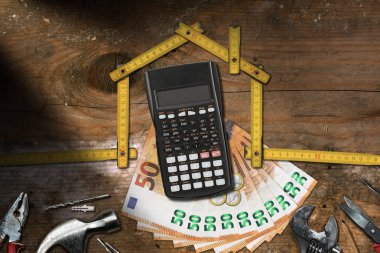 Ev geliştirme kavramı - bir ev ve iş araçları, hesap makinesi, banknot ve ahşap bir masa üzerine para şeklinde ahşap katlanır cetvel