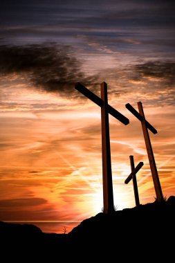 Silhouette of three wooden crosses above the hill with dramatic sky and sun rays at sunset. Religious symbol of good friday clipart