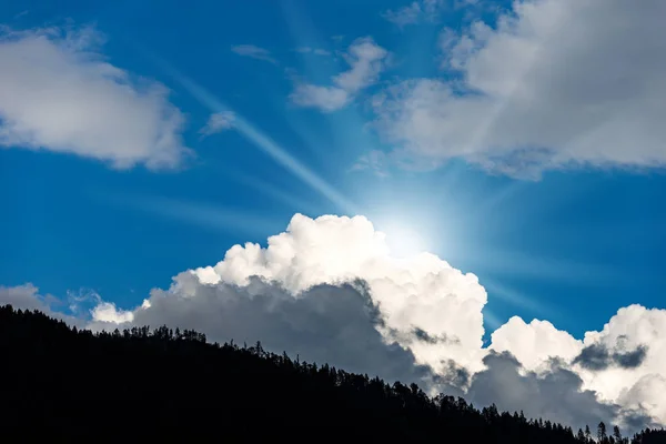 Blauer Himmel mit Wolken und Sonnenstrahlen in den Bergen — Stockfoto