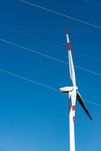 Energia odnawialna - czerwono-biała turbina wiatrowa i linia energetyczna — Zdjęcie stockowe