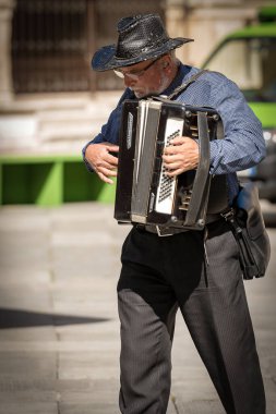 VERONA, İtalya - 17 Eylül 2016: Dante Meydanı 'nda restoranların önünde oturan turistler için tanımlanamayan kıdemli sokak müzisyeni akordeon çalıyor. Verona şehir merkezi, İtalya, Avrupa