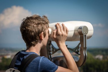 Lucca şehir merkezindeki Guinigi kulesi (Torre dei Guinigi), bozuk para kullanan bir dürbünle şehri izleyen bir genç. Toskana, İtalya, Avrupa