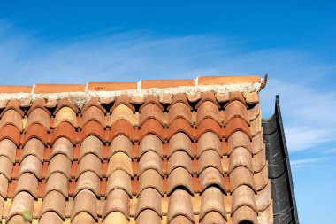 Pantiles. Terracotta fayansları (İtalyanca Coppo) olan bir çatı ve bulutlu mavi bir gökyüzünde oluk. Veneto, İtalya, Avrupa