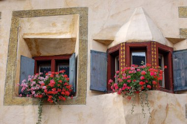 Eski Ardez, Scuol Belediyesi, Engadin Vadisi, Graubunden Kantonu, İsviçre, Avrupa 'da ahşap pencereleri ve kırmızı sardunyaları olan eski bir balkon.