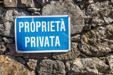 Proprieta Private, mavi-beyaz özel mülk tabelası taş duvarda asılı İtalyanca. Liguria, İtalya, Avrupa