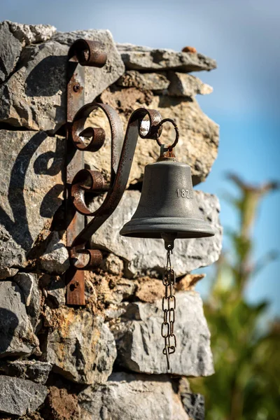 Small bell hanging on a stone wall. Tellaro village, Liguria, Italy, Southern Europe.